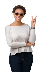 Wall Mural - Beautiful young african american woman wearing sunglasses over isolated background smiling with happy face winking at the camera doing victory sign. Number two.