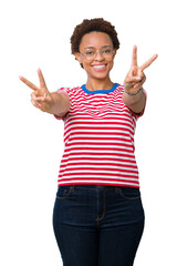 Wall Mural - Beautiful young african american woman wearing glasses over isolated background smiling looking to the camera showing fingers doing victory sign. Number two.