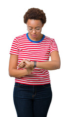 Wall Mural - Beautiful young african american woman wearing glasses over isolated background Checking the time on wrist watch, relaxed and confident