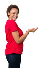 Sticker - Beautiful young african american woman wearing glasses over isolated background Pointing to the side with hand and open palm, presenting ad smiling happy and confident