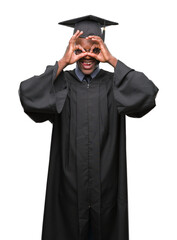 Wall Mural - Young graduated african american man over isolated background doing ok gesture like binoculars sticking tongue out, eyes looking through fingers. Crazy expression.