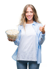 Wall Mural - Beautiful young blonde woman eating popcorn over isolated background happy with big smile doing ok sign, thumb up with fingers, excellent sign