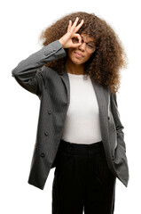 Wall Mural - African american business woman wearing glasses doing ok gesture with hand smiling, eye looking through fingers with happy face.