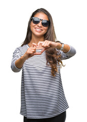 Wall Mural - Young beautiful arab woman wearing sunglasses over isolated background smiling in love showing heart symbol and shape with hands. Romantic concept.