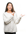 © Krakenimages.com - Young beautiful arab woman wearing winter sweater over isolated background amazed and smiling to the camera while presenting with hand and pointing with finger.