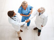 © Penn/peopleimages.com - Doctors, above and shaking hands as medical professional, partnership or consultation for collaboration. Woman, nurse and team for agreement, research and high angle in cardiology, hospital or clinic