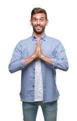 Wall Mural - Young handsome man wearing white t-shirt over isolated background praying with hands together asking for forgiveness smiling confident.