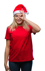 Poster - Young caucasian woman wearing christmas hat over isolated background doing ok gesture with hand smiling, eye looking through fingers with happy face.