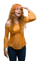 Poster - Young redhead woman very happy and smiling looking far away with hand over head. Searching concept.