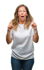 Canvas Print - Middle age senior hispanic woman over isolated background amazed and surprised looking up and pointing with fingers and raised arms.