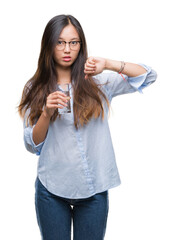 Sticker - Young asian woman drinking a glass of water over isolated background with angry face, negative sign showing dislike with thumbs down, rejection concept