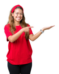 Poster - Young beautiful brunette woman wearing red t-shirt over isolated background amazed and smiling to the camera while presenting with hand and pointing with finger.