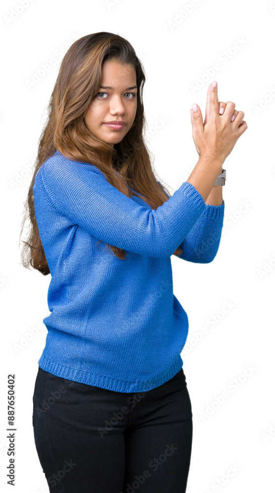 Young beautiful brunette woman wearing blue sweater over isolated background Holding symbolic gun with hand gesture, playing killing shooting weapons, angry face