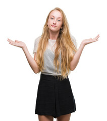 Sticker - Blonde teenager woman wearing moles shirt clueless and confused expression with arms and hands raised. Doubt concept.