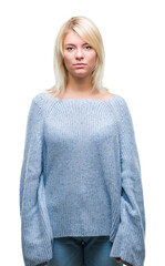 Canvas Print - Young beautiful blonde woman wearing winter sweater over isolated background with serious expression on face. Simple and natural looking at the camera.