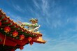 © kravtzov - A colorful Chinese Temple pagoda top decorated with lanterns, ornaments and a dragon on the blue sky background.
