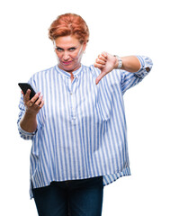 Poster - Atrractive senior caucasian redhead woman texting using smartphone over isolated background with angry face, negative sign showing dislike with thumbs down, rejection concept