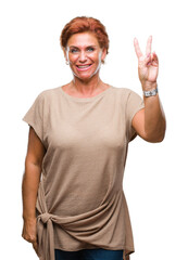 Canvas Print - Atrractive senior caucasian redhead woman over isolated background smiling with happy face winking at the camera doing victory sign. Number two.