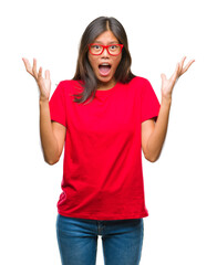 Wall Mural - Young asian woman wearing glasses over isolated background celebrating mad and crazy for success with arms raised and closed eyes screaming excited. Winner concept