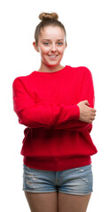 Poster - Young blonde woman wearing bun and red sweater happy face smiling with crossed arms looking at the camera. Positive person.