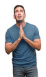 © Krakenimages.com - Handsome young casual man begging and praying with hands together with hope expression on face very emotional and worried. Asking for forgiveness. Religion concept.