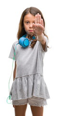 Poster - Brunette hispanic girl wearing headphones with open hand doing stop sign with serious and confident expression, defense gesture