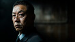 © GustavsMD - Close-up portrait of a man in a dark suit with a stern expression, set against a shadowy background. The dramatic lighting highlights his serious demeanor, creating a powerful and intense atmosphere
