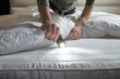 © BetterPhoto - A person inspecting a mattress for bedbugs with a flashlight, illustrating a home inspection and pest control concept.