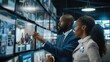 © 4​Creations Photo  - Medium shot of Biracial male security officer bringing snacks and coffee for lunch break to female Black colleague monitoring CCTV footage in surveillance room.