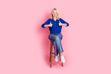 Sticker - Full body photo of attractive retired woman sit chair thumb up dressed stylish blue clothes isolated on pink color background