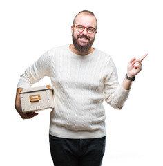 Poster - Young hipster man wearing glasses, moving holding moving box over isolated background very happy pointing with hand and finger to the side