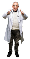 Poster - Handsome senior doctor man wearing medical coat pointing fingers to camera with happy and funny face. Good energy and vibes.