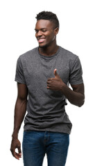 Wall Mural - Young african american man wearing grey t-shirt doing happy thumbs up gesture with hand. Approving expression looking at the camera with showing success.