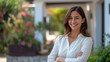 © Silard - Portrait of a beautiful smiling female wearing business costume as a real estate agent standing in front of a luxury house with her arms crossed looking at the camera