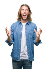 Canvas Print - Young handsome man with long hair over isolated background crazy and mad shouting and yelling with aggressive expression and arms raised. Frustration concept.