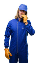 Canvas Print - Young handsome mechanic man with long hair over isolated background looking stressed and nervous with hands on mouth biting nails. Anxiety problem.