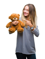 Sticker - Young beautiful blonde woman holding teddy bear plush over isolated background very happy pointing with hand and finger