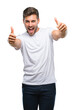 © Krakenimages.com - Young handsome man over isolated background approving doing positive gesture with hand, thumbs up smiling and happy for success. Looking at the camera, winner gesture.