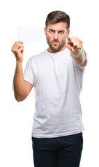 Poster - Young handsome man holding blank card over isolated background pointing with finger to the camera and to you, hand sign, positive and confident gesture from the front