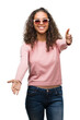 © Krakenimages.com - Beautiful young hispanic woman wearing sunglasses looking at the camera smiling with open arms for hug. Cheerful expression embracing happiness.