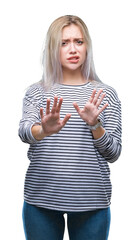 Sticker - Young blonde woman over isolated background disgusted expression, displeased and fearful doing disgust face because aversion reaction. With hands raised. Annoying concept.