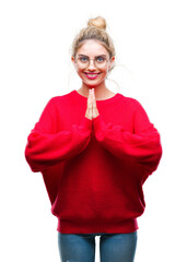 Sticker - Young beautiful blonde woman wearing red sweater and glasses over isolated background praying with hands together asking for forgiveness smiling confident.