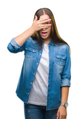 Sticker - Young caucasian beautiful woman over isolated background peeking in shock covering face and eyes with hand, looking through fingers with embarrassed expression.