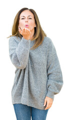 Poster - Beautiful middle age woman wearing winter sweater over isolated background looking at the camera blowing a kiss with hand on air being lovely and sexy. Love expression.