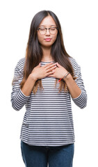 Wall Mural - Young asian woman wearing glasses over isolated background smiling with hands on chest with closed eyes and grateful gesture on face. Health concept.