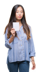 Wall Mural - Young asian woman holding notebook over isolated background with a confident expression on smart face thinking serious