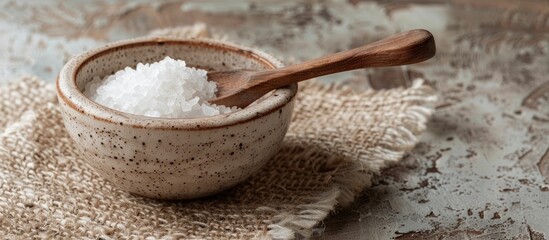 Fototapete - A tiny ceramic bowl with salt and an olive wood spoon perfect for a rustic kitchen feel isolated in a beautiful setting with a blank background as a copy space image