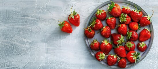 Poster - A vibrant array of ripe strawberries is placed on a gray plate against a light wooden backdrop creating a vibrant copy space image with a focus on a juicy red berry promoting healthy vegetarian detox