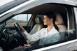 © SHOTPRIME STUDIO - Woman, driver, car interior a woman with a confident expression sits in the driver's seat of a car, her hand resting on the steering wheel while she looks directly at the camera