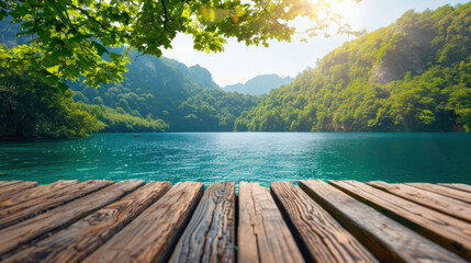 Poster - Tranquil lakeside view with clear blue water and lush green mountains in the background, captured from a wooden dock under bright sunlight.